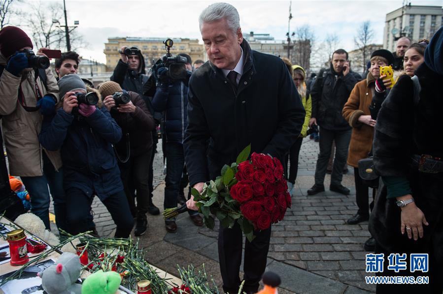3月27日，在俄罗斯首都莫斯科，莫斯科市长索比亚宁（中）摆放鲜花悼念克麦罗沃火灾遇难者。