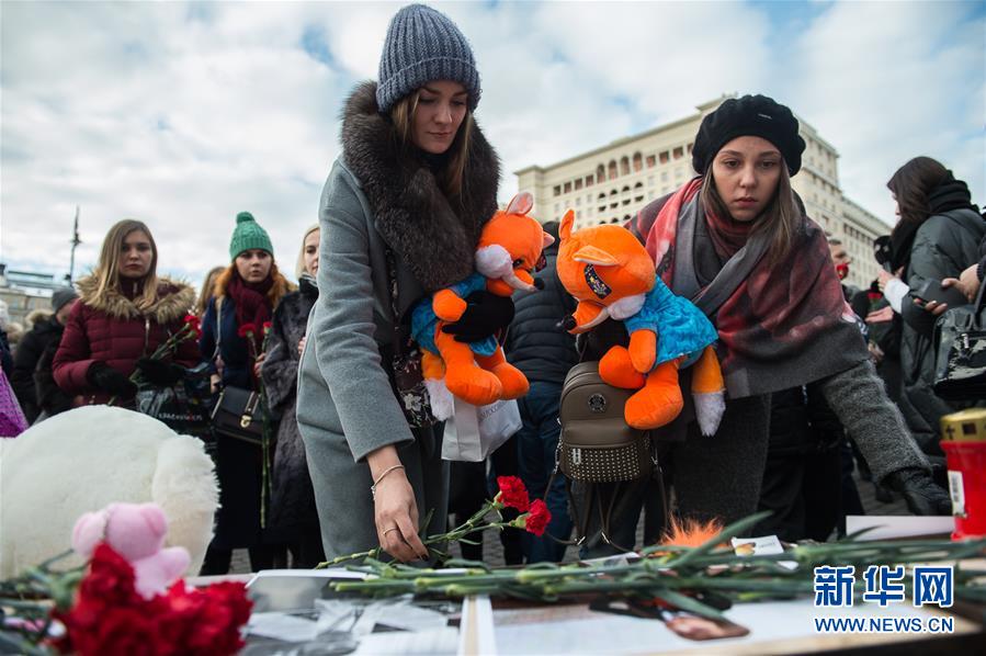 月27日，在俄罗斯首都莫斯科，两名女子摆放鲜花悼念克麦罗沃火灾遇难者。